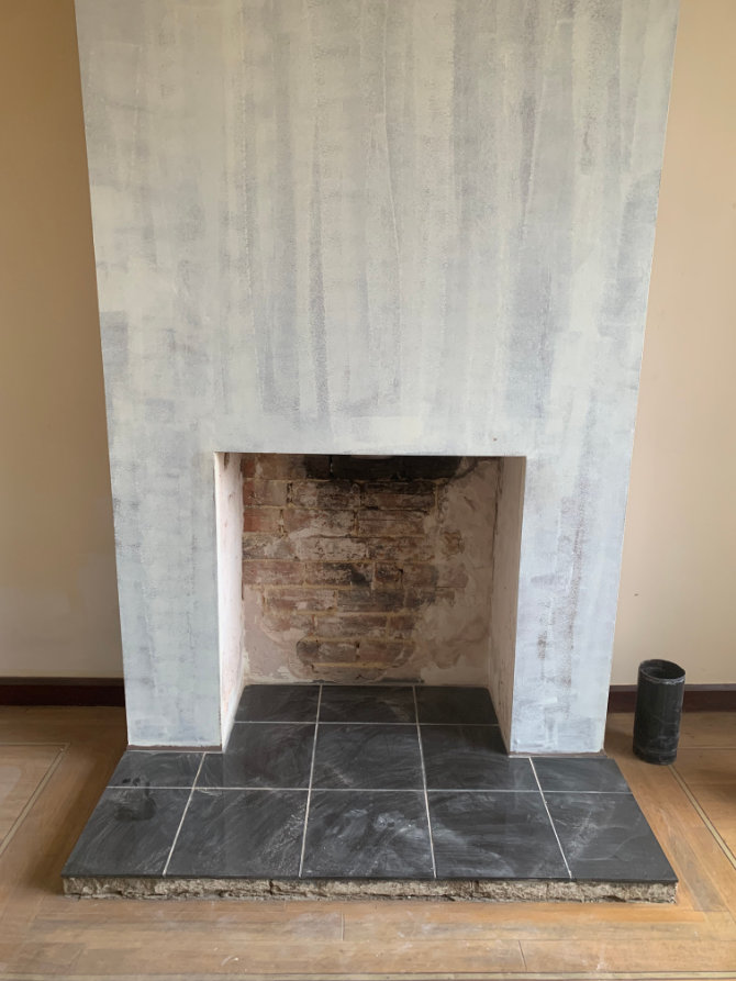 Fireplace before restoration with cracked plaster